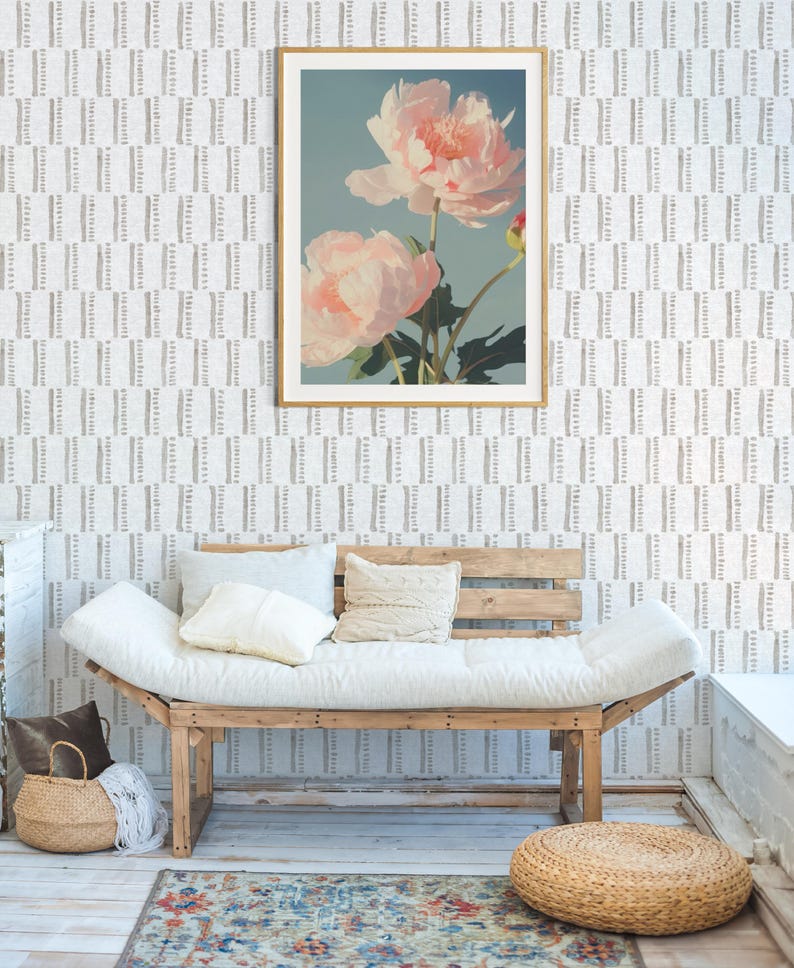 Pu&ograve; includere: Una stampa floreale incorniciata con due grandi fiori di peonia rosa chiaro su uno sfondo azzurro. La stampa con cornice dorata &egrave; appesa sopra un futon di legno con cuscini e cuscini bianchi. Un cesto intrecciato e un tappeto sono in primo piano.