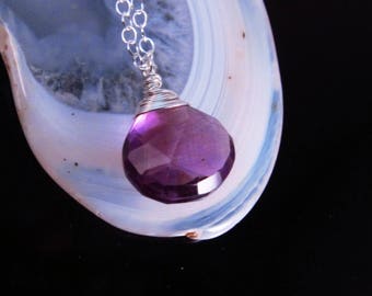 May include: A silver chain necklace with a purple gemstone pendant. The pendant is faceted and has a teardrop shape.