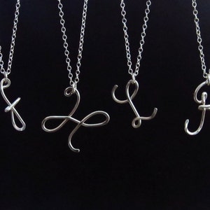 May include: Five silver necklaces with different initial pendants. The pendants are made of thin wire and are in a cursive style. The initials are D, K, Z, L, and R.