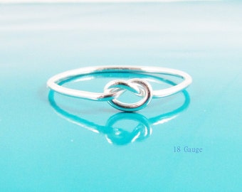 Könnte beinhalten: Ein silberner Knotenring mit schlichtem Design. Der Ring ist 18 Gauge.