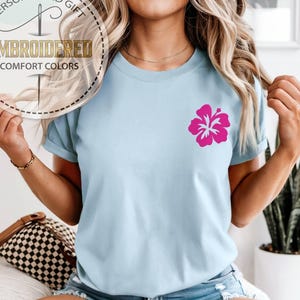 Op de afbeelding: Een witte keramische mok met een zwarte handgreep en de tekst "But First, Coffee" in een vetgedrukte, zwarte letter. De mok staat tegen een wazige achtergrond, wat een gezellige setting suggereert.