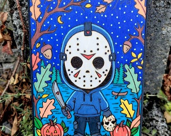 May include: A rectangular wooden plaque featuring a colorful illustration of a hockey mask-wearing character in a blue hoodie holding a knife. The scene includes a starry night sky, autumn leaves, acorns, and two jack-o'-lanterns on the ground.