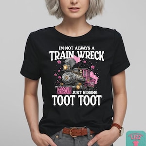 May include: Black t-shirt with the text "I'm Not Always a Train Wreck Just Kidding Toot Toot". The graphic features a pink and gray train with pink floral accents. The shirt is worn by a person.