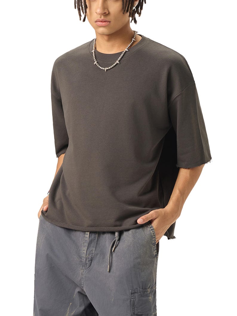 A dark gray, half-sleeved t-shirt with a raw hem and a crew neck. The shirt is paired with gray cargo pants with a drawstring. A silver necklace with spike-like accents is worn.