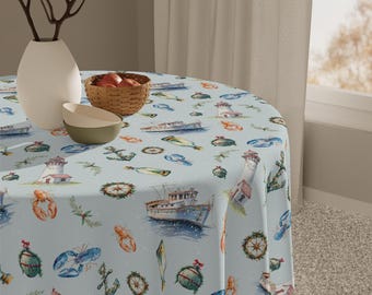 May include: A round tablecloth with a light blue background featuring watercolor illustrations of nautical elements. The design includes boats, lobsters, anchors, and lighthouses. The tablecloth is draped over a round table, creating a coastal theme.