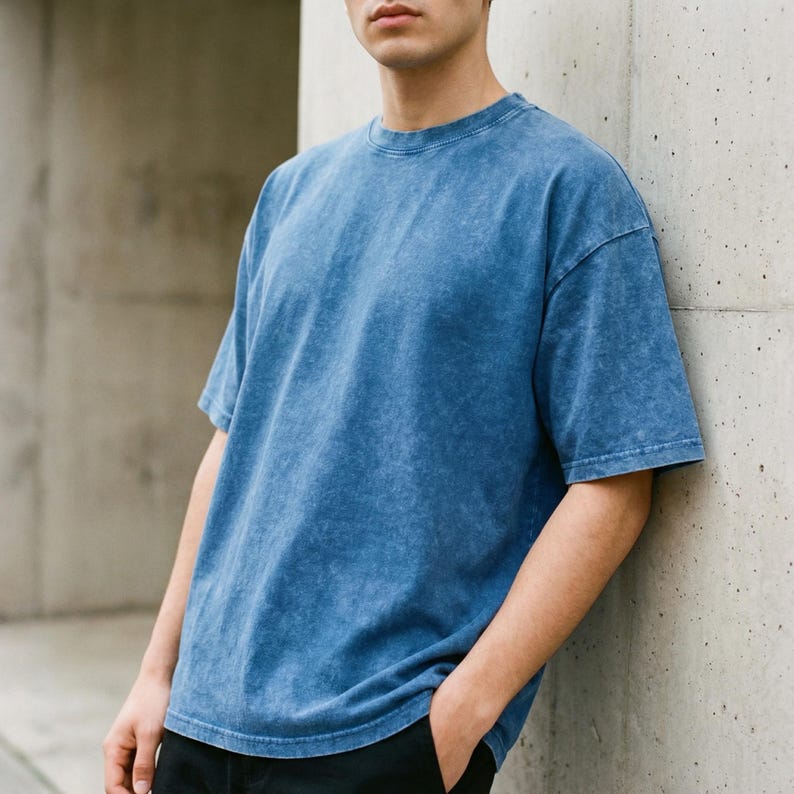 Op de afbeelding: Een t-shirt met korte mouwen in een medium blauwe kleur met een gewassen, gevlekte textuur. Het kledingstuk heeft een ronde hals, een relaxte pasvorm en een rechte zoom, met een consistente blauwe tint over het gehele oppervlak.