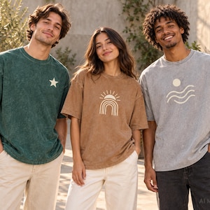Three models wearing custom acid wash oversized T-shirts in dark green, light brown, and light gray with personalized printed graphics.
