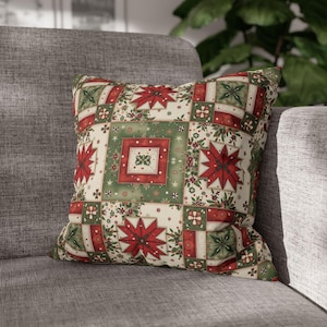 Puede incluir: Cojín decorativo cuadrado con diseño de patchwork. Presenta flores de pascua rojas, cuadrados verdes y detalles florales sobre fondo crema. Ideal para la decoración del hogar.
