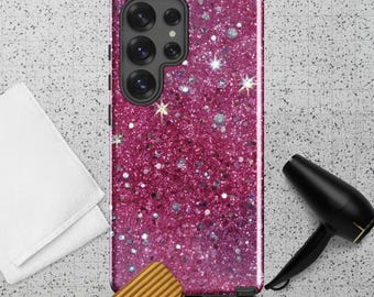May include: A magenta glitter phone case with a multi-lens camera. The case is surrounded by a white towel, a wooden comb, and a black hairdryer. The background is a light gray surface with a subtle pattern.