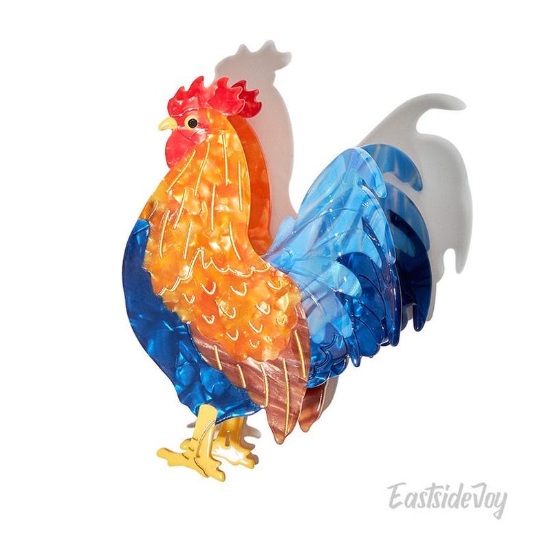 May include: A colorful rooster figurine with a vibrant design. The rooster features a red comb, orange body, and blue tail feathers. The figurine has gold-colored feet and a white shadow.