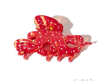 May include: A red octopus-shaped hair claw clip with white polka dots. The clip has a glossy finish and is designed to hold hair in place. The design includes the text "EastsideJoy".