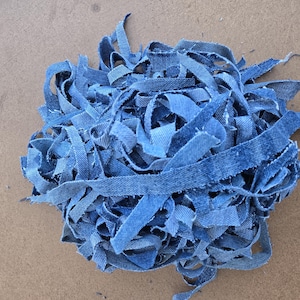 Könnte beinhalten: Ein Haufen blauer Jeansstoffreste. Der Stoff ist in lange Streifen geschnitten und ist verheddert.