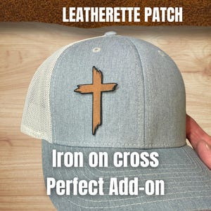 May include: A gray trucker hat with a white mesh back and a brown cross patch. The hat has the text "LEATHERETTE PATCH" at the top and "Iron on cross Perfect Add-on" at the bottom.