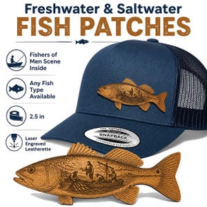 May include: A navy blue trucker hat with a mesh back and a laser-engraved brown leatherette fish-shaped patch featuring a scene of fishers in a boat. The patch measures 2.5 inches. Text includes Freshwater & Saltwater FISH PATCHES.