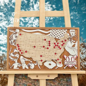 Può includere: Mappa di viaggio di baseball in legno degli Stati Uniti con indicatori di baseball rossi. La mappa include sagome di giocatori di baseball, una bandiera americana e il testo "DECLERCO FAMILY BASEBALL TRAVEL MAP".