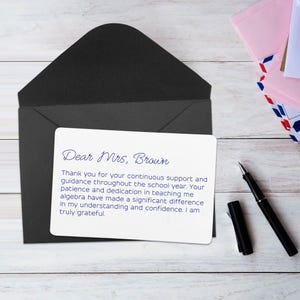 May include: A white card with a handwritten message inside a black envelope. The message is addressed to "Mrs. Brown" and expresses gratitude for her support and guidance. A black pen and other envelopes are also visible.