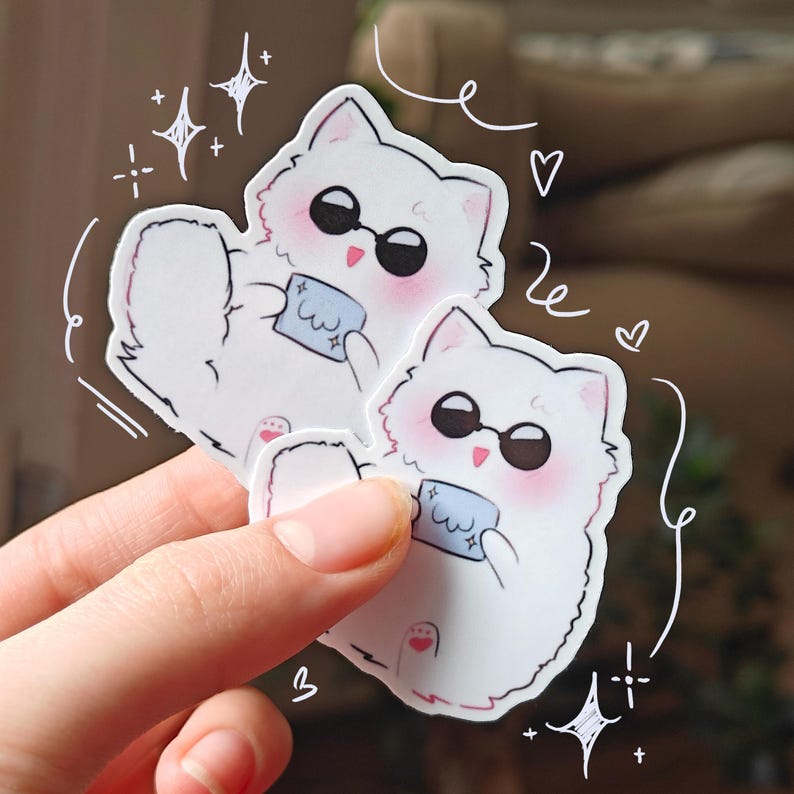Cute Gojo Satoru-inspired cat sticker featuring a chibi-style white fluffy cat with sunglasses, blushing cheeks, and holding a tiny blue cloth. A fun Jujutsu Kaisen anime vinyl sticker perfect for decorating water bottles, journals, phone cases, or laptops.