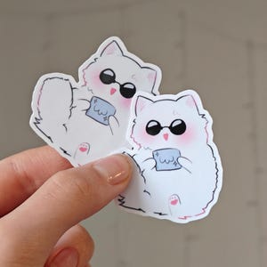 Adorable Gojo Satoru cat sticker featuring a fluffy white chibi cat with sunglasses and a tiny blue cloth. Inspired by Jujutsu Kaisen, this kawaii anime vinyl sticker is great for decorating laptops, water bottles, phone cases, journals, and more!