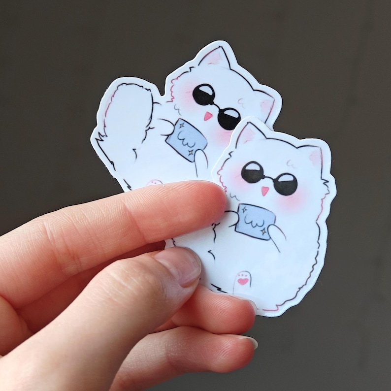 Gojo Satoru as an adorable fluffy cat! This cute anime vinyl sticker is inspired by Jujutsu Kaisen, featuring a white cat with sunglasses and a tiny blue cloth. Great for laptops, water bottles, notebooks, scrapbooking, and anime merch collectors.