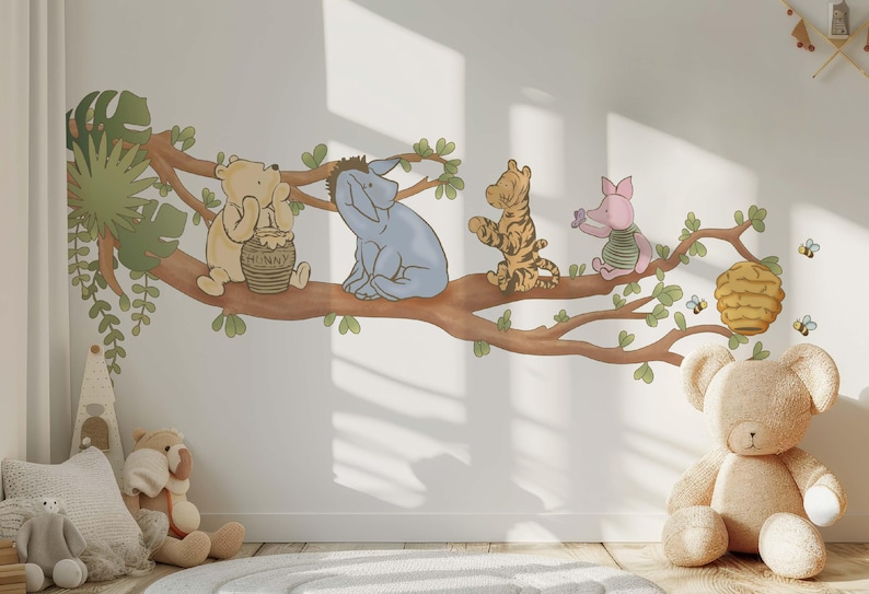 Op de afbeelding: Een Winnie de Poeh-muursticker met Winnie de Poeh, Biggetje, Eeyore en Teigetje die op een tak zitten. De sticker is perfect voor een kinderkamer of babykamer.