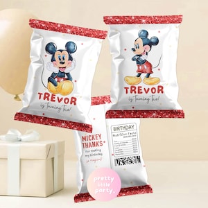 May include: White party favor bags with a red glitter border and Mickey Mouse graphics. The bags read "TREVOR is turning two!" and "MICKEY THANKS for making my birthday so magical!" A "BIRTHDAY" nutrition facts label is also visible.