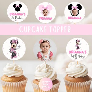 Puede incluir: Cupcakes con adornos personalizados con el tema de Minnie Mouse. Algunos adornos presentan una foto de una ni&ntilde;a, otros muestran ilustraciones de Minnie Mouse y el texto "Brianna's 3rd Birthday". Los cupcakes tienen glaseado blanco.