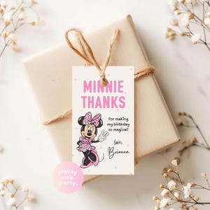 Puede incluir: Un regalo envuelto en papel beige y atado con hilo, con una etiqueta de agradecimiento de Minnie Mouse. La etiqueta tiene texto rosa que dice "MINNIE THANKS" y una ilustraci&oacute;n de dibujos animados de Minnie Mouse. La etiqueta tambi&eacute;n incluye el texto "for making my birthday so magical!" y "love, Brianna."
