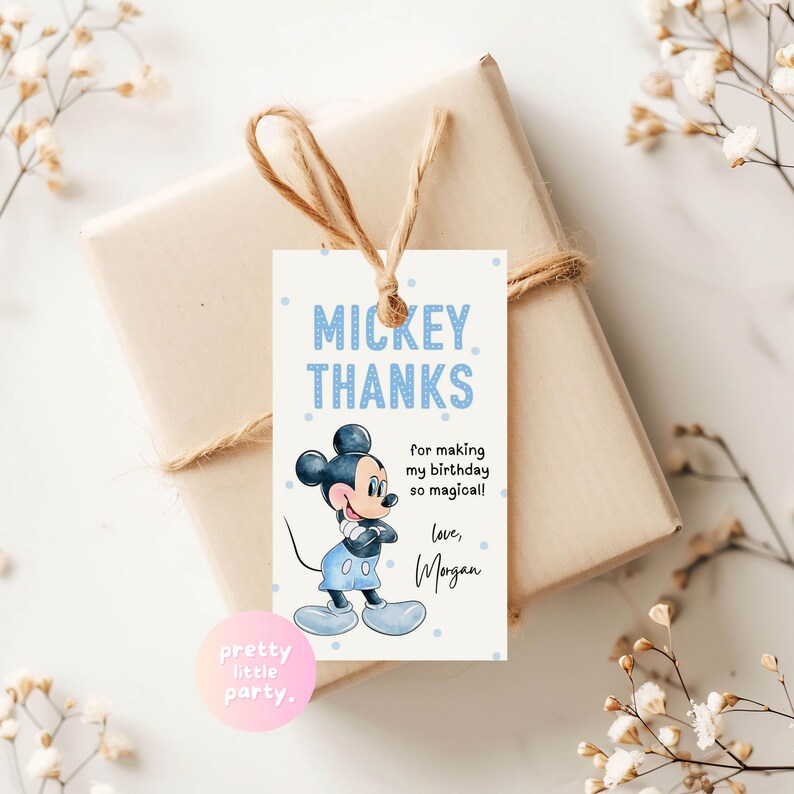 Puede incluir: Una etiqueta de regalo con una ilustraci&oacute;n de Mickey Mouse y la frase azul "MICKEY THANKS". La etiqueta dice "for making my birthday so magical! love, Morgan." La etiqueta est&aacute; atada a un regalo envuelto con hilo.