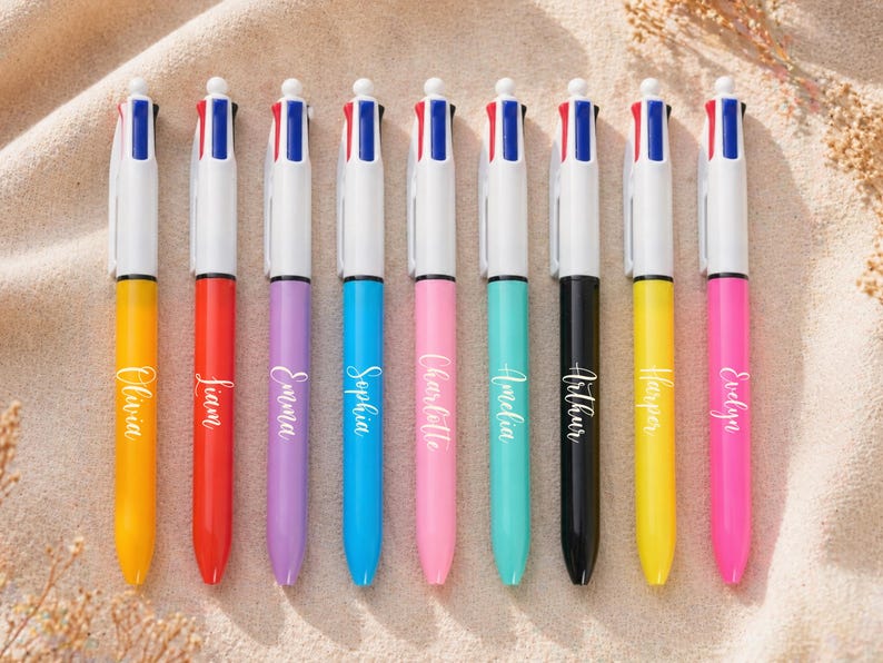 May include: Nine colorful multi-color pens with names printed on them. The pens have white barrels and are in various colors, including yellow, red, purple, blue, pink, teal, black, and yellow. Each pen has a different name printed on it.