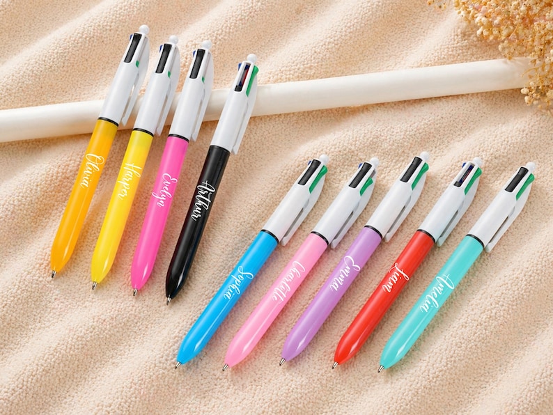 May include: A collection of colorful multi-color pens with white barrels. Each pen has a different colored barrel and the names Olivia, Harper, Evelyn, Arthur, Sophia, Charlotte, Emma, Liam, and Amelia are printed on the pens.