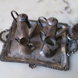 May include: A silver tea set on a silver tray. The set includes a teapot, creamer, and two sugar bowls.