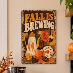 May include: A rectangular metal wall sign with the text FALL IS BREWING, featuring a coffee pot, a cup, a donut, and autumn leaves. The sign is displayed in a kitchen setting with a stainless steel espresso machine, ceramic canisters, and mugs.