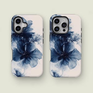 Może przedstawiać: Dwa etui na telefon z niebieskim kwiatowym wzorem. Etui są białe z dużym, abstrakcyjnym niebieskim kwiatowym wzorem. Kwiat ma wiele warstw płatków i ciemny środek. Etui mają czarne boczne akcenty.