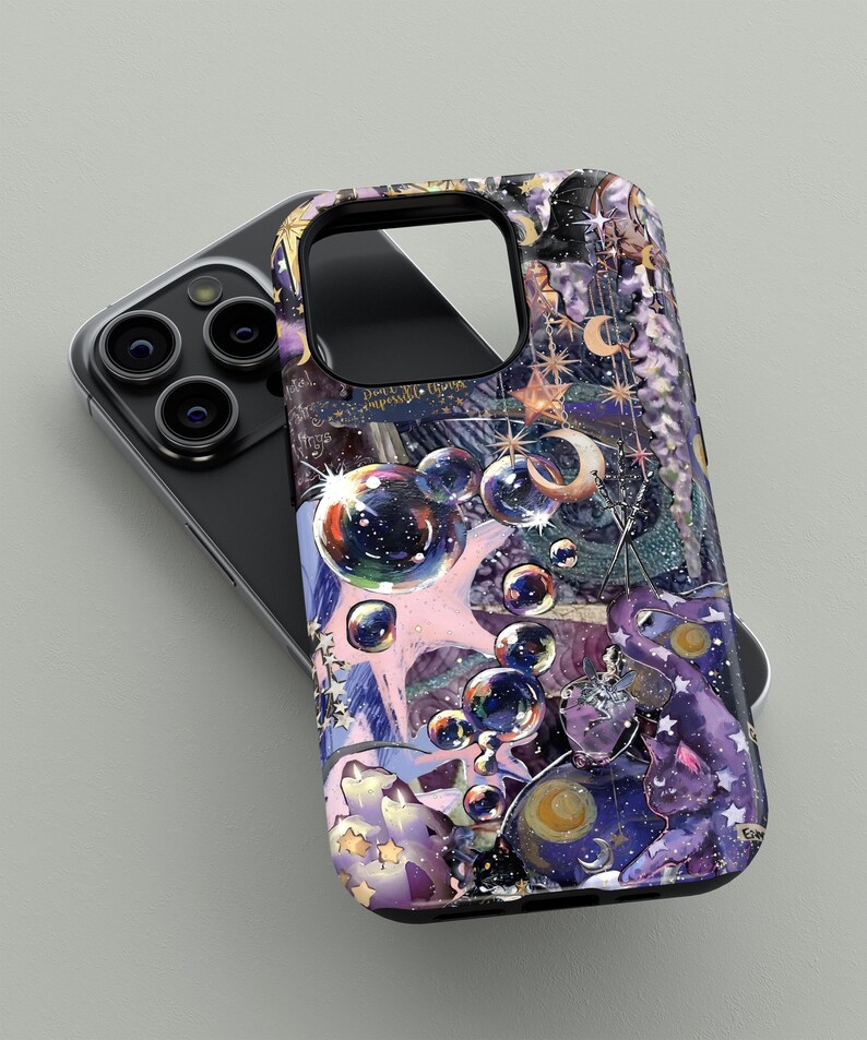 May include: A phone case with a colorful, artistic design featuring bubbles, stars, and celestial elements in shades of purple, pink, and gold. The case is shown on top of a black phone.
