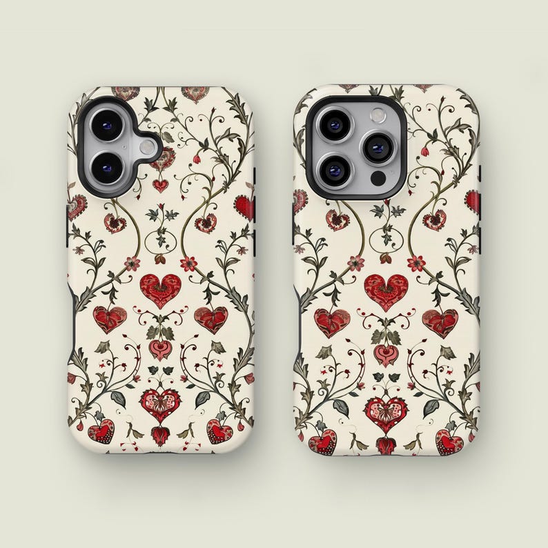 May include: Two phone cases with a cream background and a repeating pattern of red hearts, flowers, and vines. The design has a vintage, romantic aesthetic. The cases are designed to fit a smartphone.
