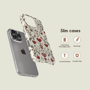 May include: A silver smartphone with a decorative phone case. The case features a cream background with red hearts and floral patterns. The text "Slim cases" is displayed with icons for features like "Long Lasting Personality Colors" and "Scratch Resistant".