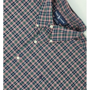 May include: A button-down shirt with a plaid pattern in navy, red, and green. The shirt has a classic collar and white buttons. The Ralph Lauren logo is visible on the label.