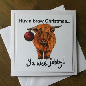 Square card with highland cow wearing a Christmas bauble.