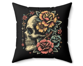 May include: Square black throw pillow featuring a detailed illustration of a skull surrounded by colorful flowers. The skull is cream-colored, and the flowers are in shades of red, yellow, and blue. The design has a tattoo-inspired aesthetic.
