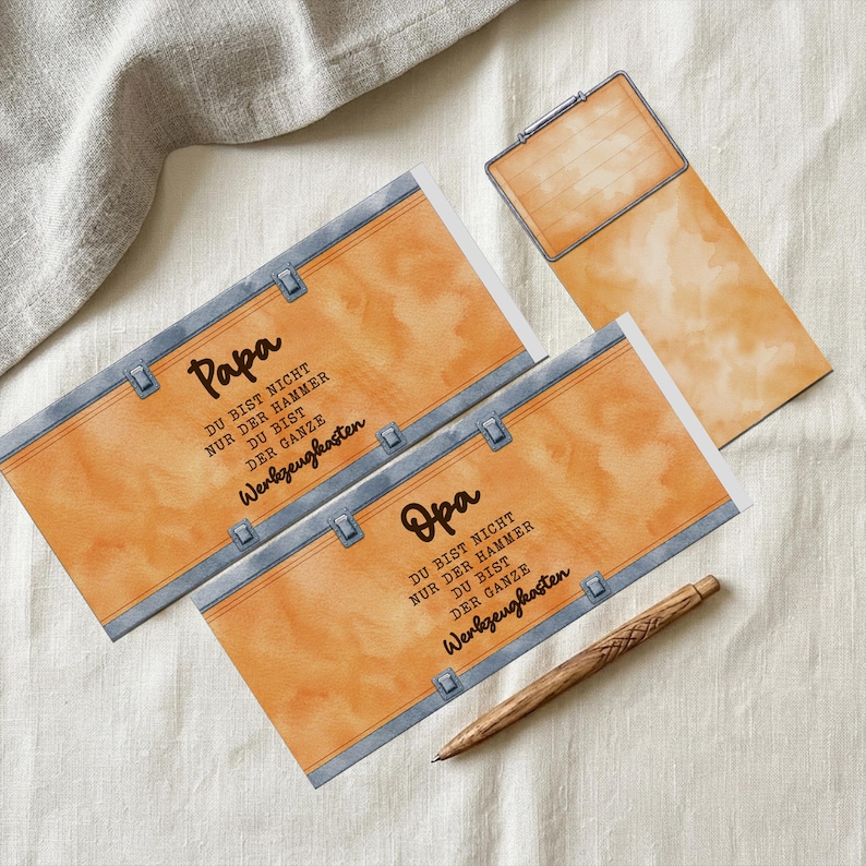 Pode incluir: Um conjunto de artigos de papelaria com um design em aquarela. O conjunto inclui dois cart&otilde;es com a palavra "Papa" e um com "Opa", um bloco de notas e uma caneta de madeira. Os cart&otilde;es t&ecirc;m um design de couro sint&eacute;tico com texto em alem&atilde;o.