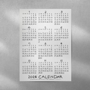 Puede incluir: Un calendario de papel blanco para el año 2026, con un estilo manuscrito. Cada mes se muestra con los días de la semana y las fechas. La palabra "CALENDAR" está en la parte inferior.
