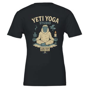 Puede incluir: Camiseta negra con un diseño de un yeti meditando. El diseño incluye el texto "Yeti Yoga Studio" y "Find Your Inner Chill". El yeti está rodeado de cristales, una vela y setas.
