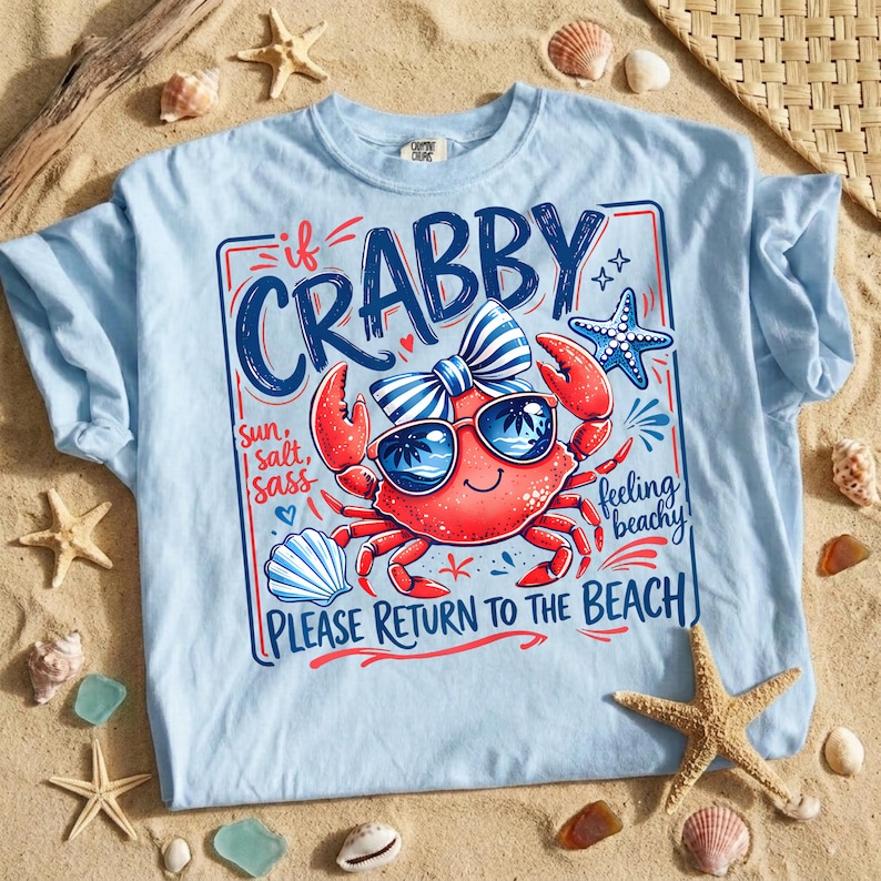 May include: Light blue t-shirt with a graphic of a red crab wearing sunglasses and a bow tie. The text on the shirt reads "If Crabby, Please Return to the Beach." The design includes a starfish and seashell.