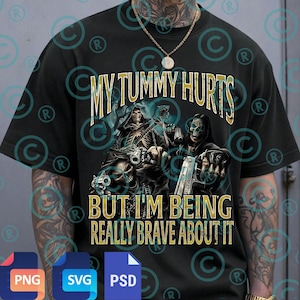 May include: Black t-shirt featuring a graphic of two grim reapers with guns and skulls. The text "MY TUMMY HURTS BUT I'M BEING REALLY BRAVE ABOUT IT" is printed in gold. The shirt has short sleeves.