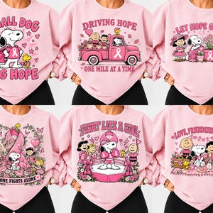 Op de afbeelding: Een collectie van zes lichtroze sweatshirts met Peanuts-karakterafbeeldingen gerelateerd aan borstkankerbewustzijn. Elk shirt toont unieke illustraties van Snoopy en vrienden met roze linten, hartjes en inspirerende teksten zoals Small Dog Big Hope, Driving Hope, Let Hope Grow, No One Fights Alone, Fight Like A Girl en Love, Friendship & Hope.
