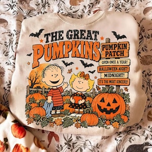 May include: A cream-colored crewneck sweatshirt featuring a graphic print of two cartoon characters in a pumpkin patch. The text reads THE GREAT PUMPKINS, PUMPKIN PATCH, OPEN ONCE A YEAR, HALLOWEEN NIGHT, MIDNIGHT, and IT'S THE MOST SINCERE, with bats.