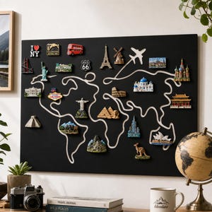 May include: A black rectangular wall map featuring a white outline of the world continents. The map is decorated with various colorful 3D travel magnets representing landmarks like the Eiffel Tower, Statue of Liberty, pyramids, and a red bus.