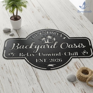 Puede incluir: Letrero de metal negro con el texto "The Kathryn's Backyard Oasis" y las palabras "Relax, Unwind, Chill" debajo. El letrero tambi&eacute;n incluye el a&ntilde;o "EST. 2026". El letrero tiene un borde decorativo y siluetas de palmeras.