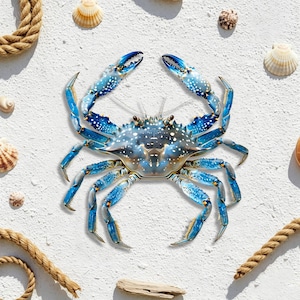 May include: A detailed image of a blue crab with white spots, surrounded by seashells and rope on a white sandy surface. The crab's claws are open, and the image has a bright, summery feel. The crab is the focal point.
