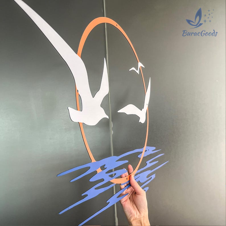 May include: A decorative wall art piece featuring white seagulls soaring against an orange sun. Below, blue wave-like shapes add a coastal theme. The artwork includes the text "BuracGoods".
